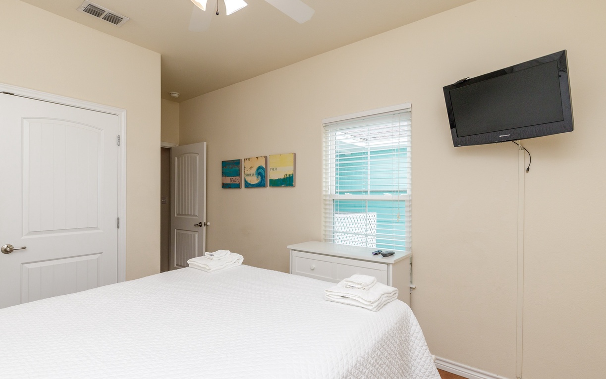 Unwind in your peaceful bedroom featuring crisp linens, wall-mounted TV for cozy nights, and bright windows creating an airy retreat.