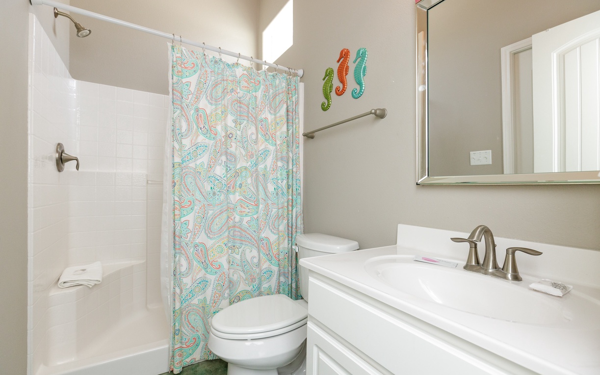 Your bright bathroom features a spacious shower-tub combo with cheerful seahorse decor, creating a welcoming coastal vibe for your stay.