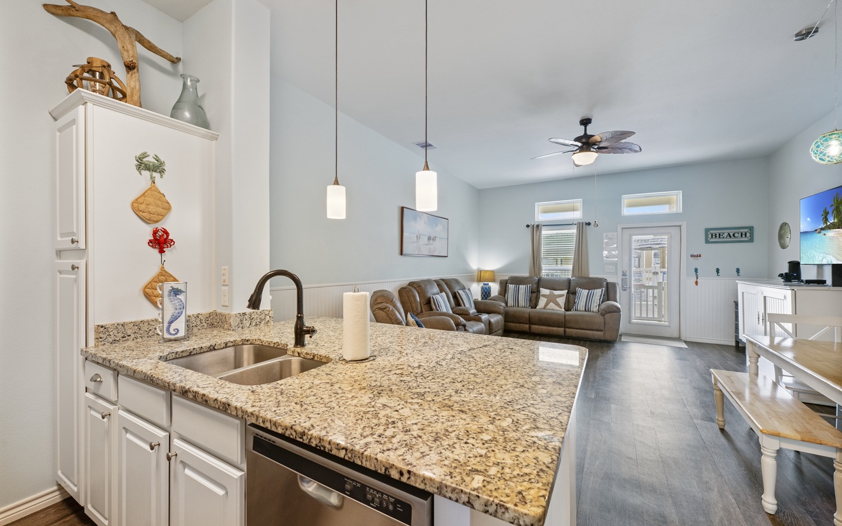 Your open kitchen flows seamlessly into the living area, where granite countertops and coastal decor create the perfect space for vacation cooking and relaxing.