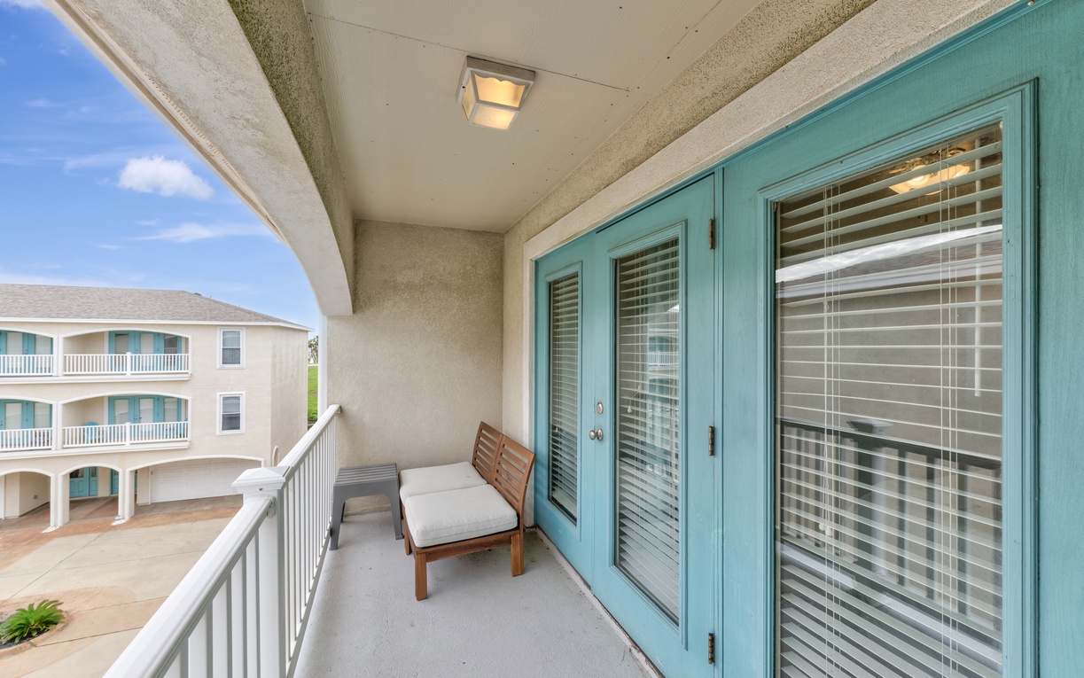 Your private balcony offers a peaceful retreat with comfortable seating and charming turquoise accents, perfect for morning coffee or evening relaxation.