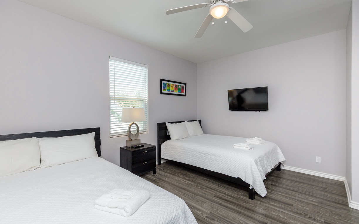 Relax in your bright bedroom with two comfortable beds, ceiling fan, flat-screen TV, and fresh towels waiting for you.