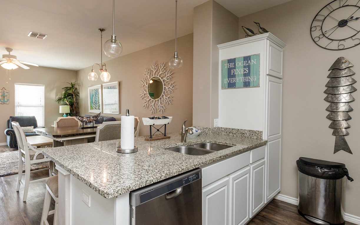 Your modern kitchen features granite counters, stainless appliances, and flows into your coastal-themed living space perfectly.