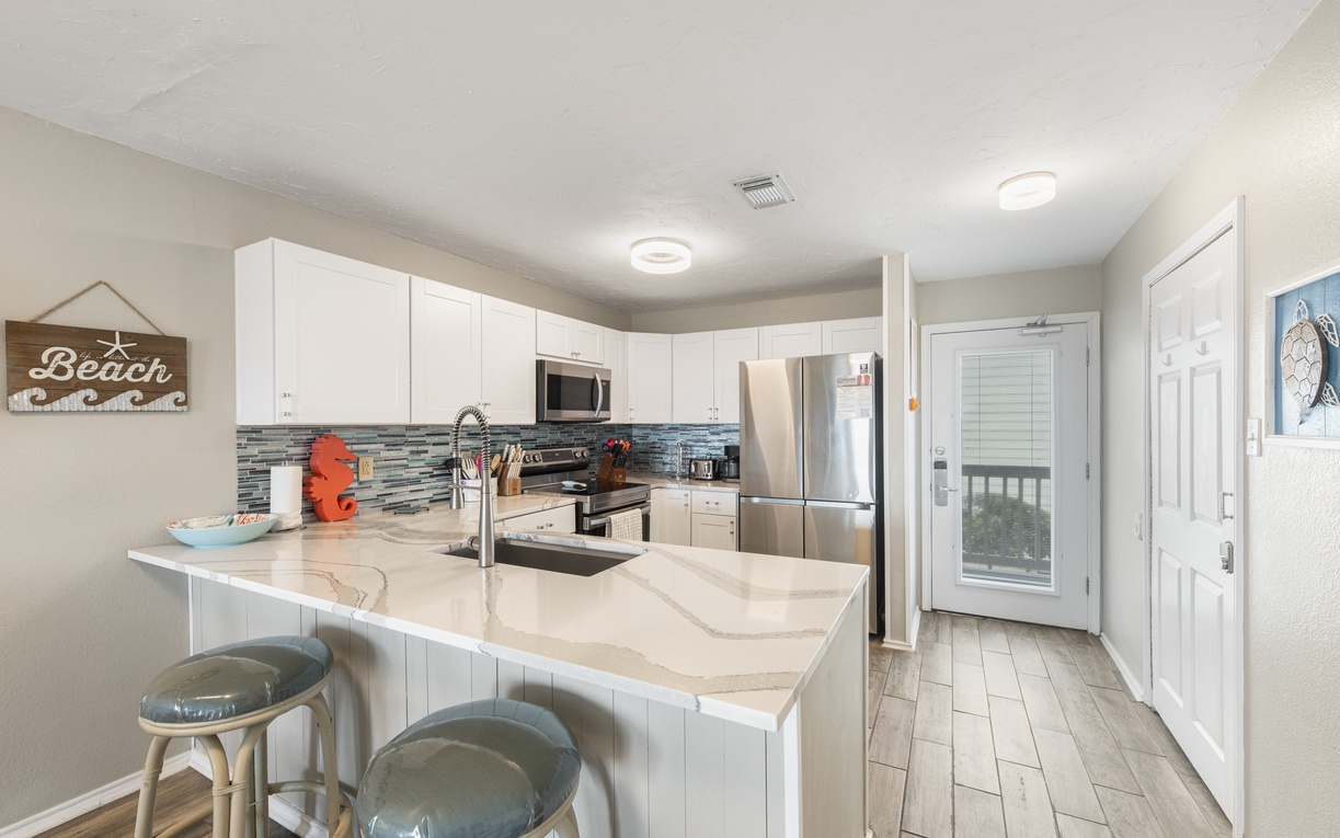 Your fully equipped kitchen awaits with modern appliances, granite countertops, and coastal charm perfect for preparing vacation meals together.