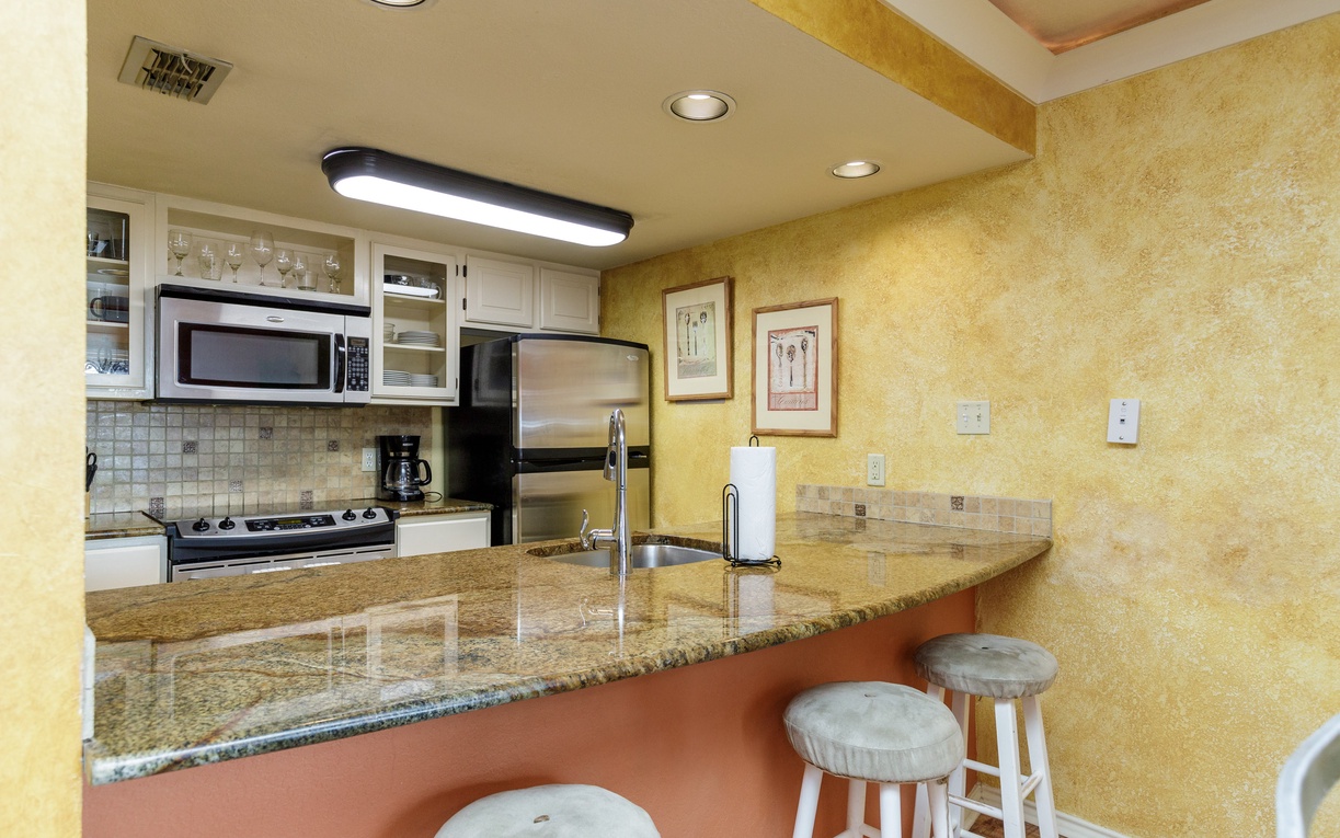Your fully equipped kitchen features granite countertops, stainless steel appliances, and a convenient breakfast bar where you can enjoy morning coffee.