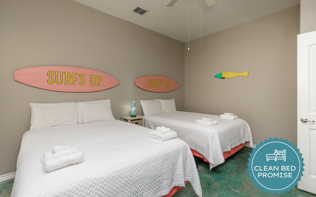 Drift off to sleep under fun surfboard art in this cozy twin bedroom, perfect for kids or friends sharing adventures.
