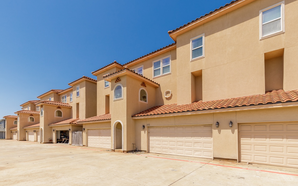 Mediterranean-style townhomes with clay tile roofs and attached garages create a welcoming residential community.
