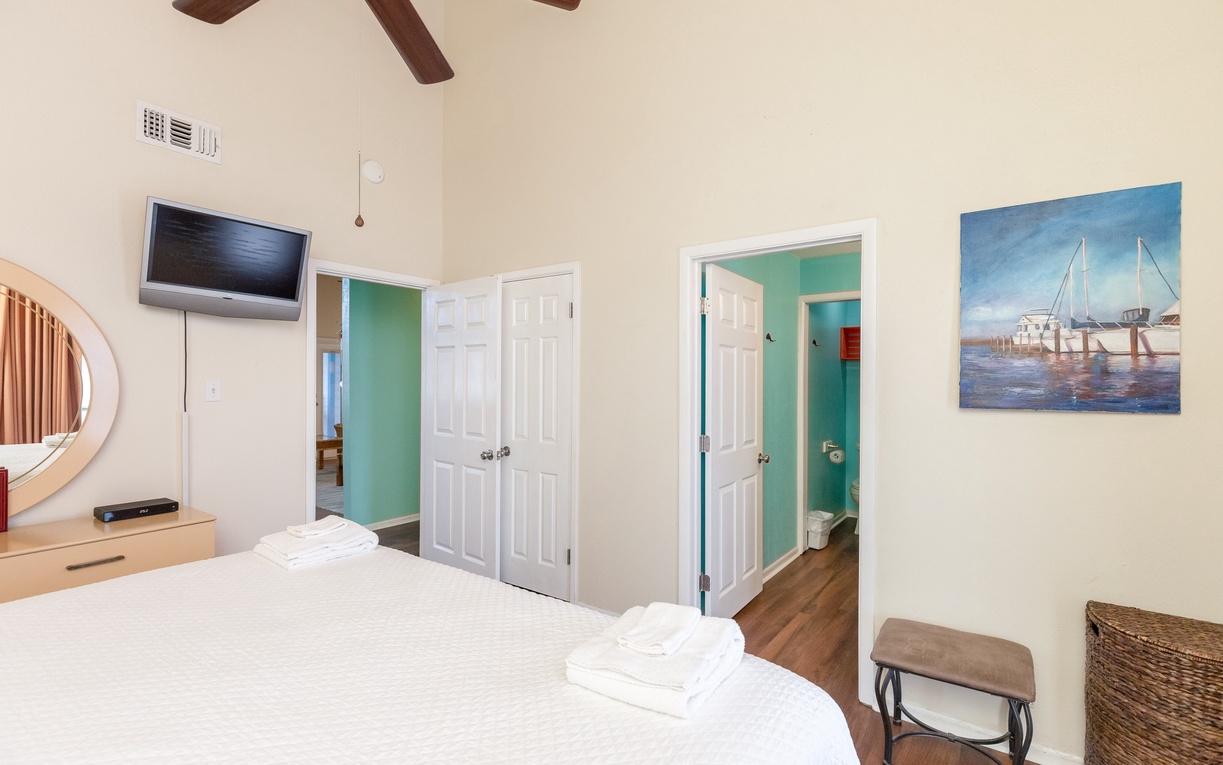 Relax in your coastal-themed bedroom with vaulted ceilings, ceiling fan, TV, and queen size bed.