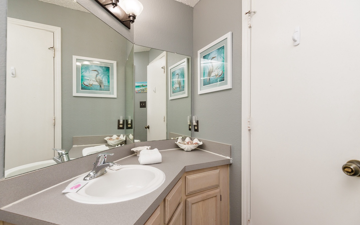 Refresh in your stylish bathroom featuring coastal artwork, plush towels, and thoughtful amenities that make your morning routine feel like a spa experience.