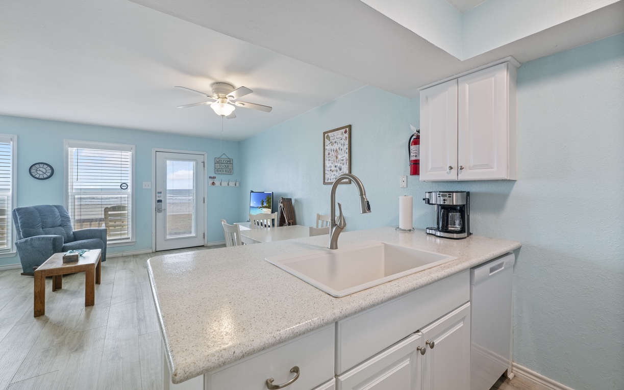 Your coastal kitchen flows seamlessly into the living area, featuring modern appliances and bright, airy décor perfect for preparing beachside meals.