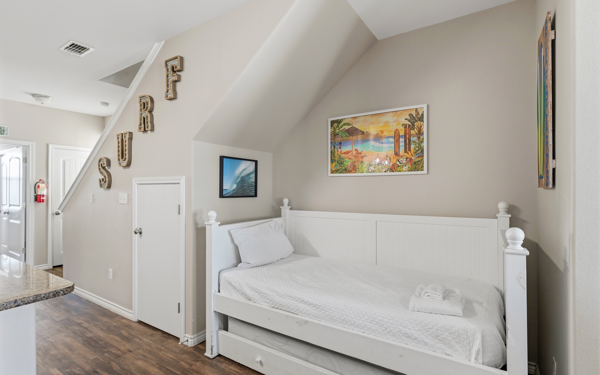 Your cozy daybed offers a peaceful retreat beneath crisp white walls and cheerful decor. Soft linens invite you to unwind, while skylights above fill the space with natural warmth—perfect for reading or afternoon naps.