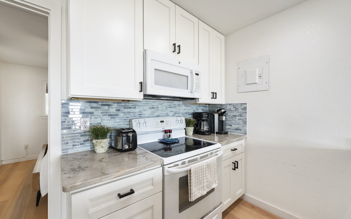 Your kitchen features beautiful marble counters, coastal-style tile backsplash, stainless appliances, and everything you need to prepare meals, including a coffee maker for easy mornings.