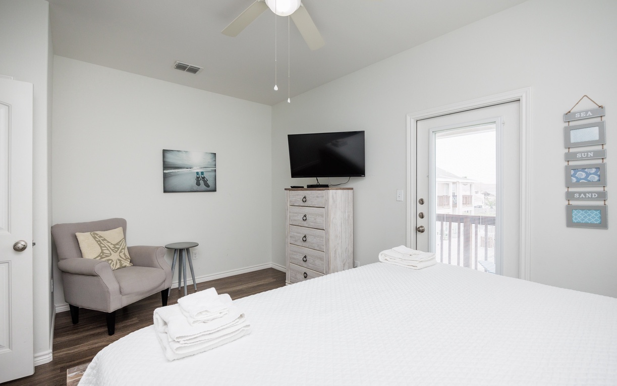 Sink into crisp white linens in your serene bedroom, where coastal artwork and a cozy reading chair create your perfect retreat.