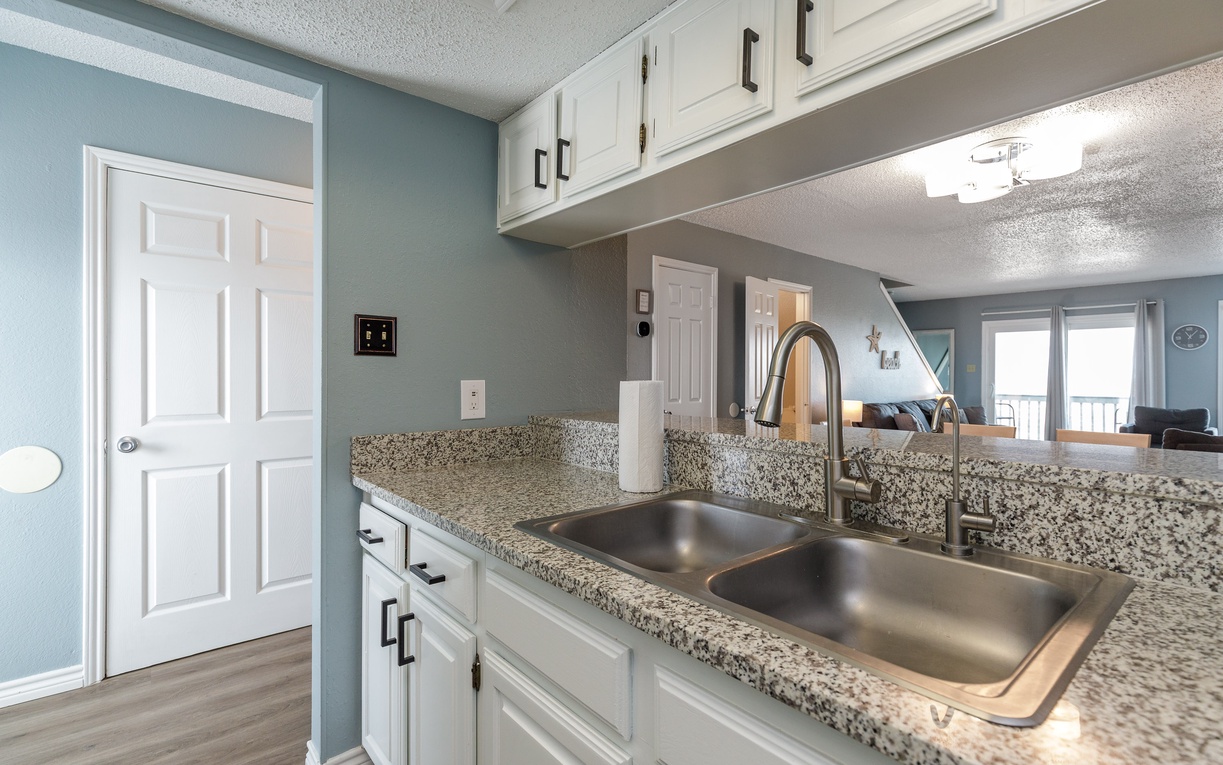 Cook your favorite meals in this bright kitchen featuring granite countertops, stainless steel sink, and modern white cabinets.