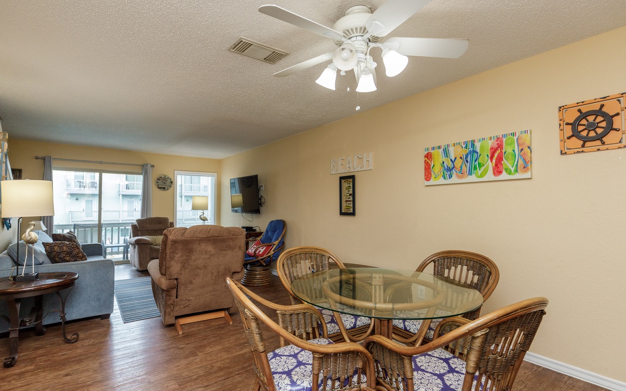 Relax in your bright, beach-themed haven with comfortable seating, ceiling fan, and cheerful coastal décor creating the perfect vacation atmosphere.
