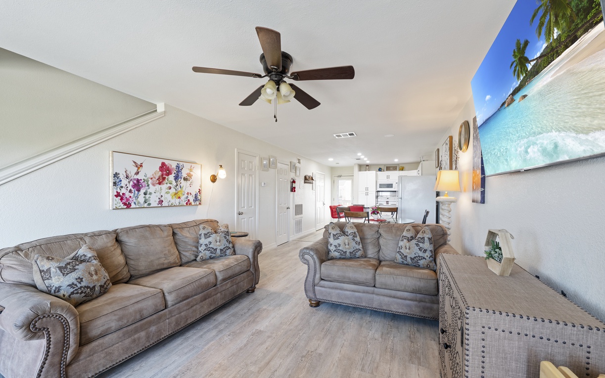 Unwind in your spacious living area with plush seating, tropical artwork, and a ceiling fan keeping you cool.