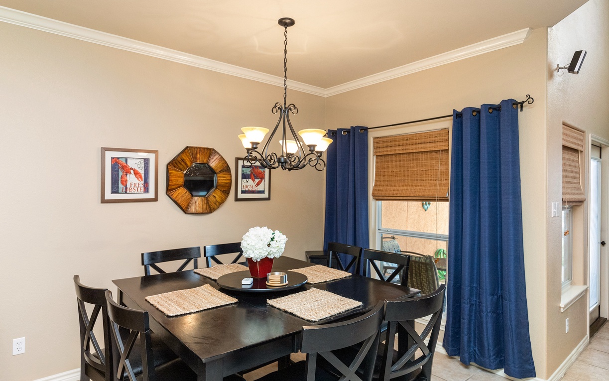 Gather around your elegant dining table for memorable meals, bathed in warm chandelier light with coastal charm.