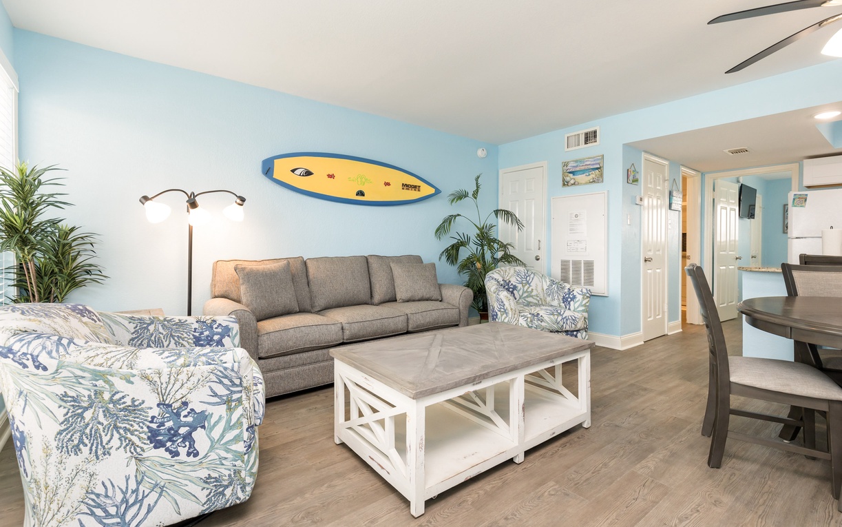 Relax in your coastal-themed living room with comfortable seating, tropical plants, and beach-inspired decor that creates the perfect vacation atmosphere.