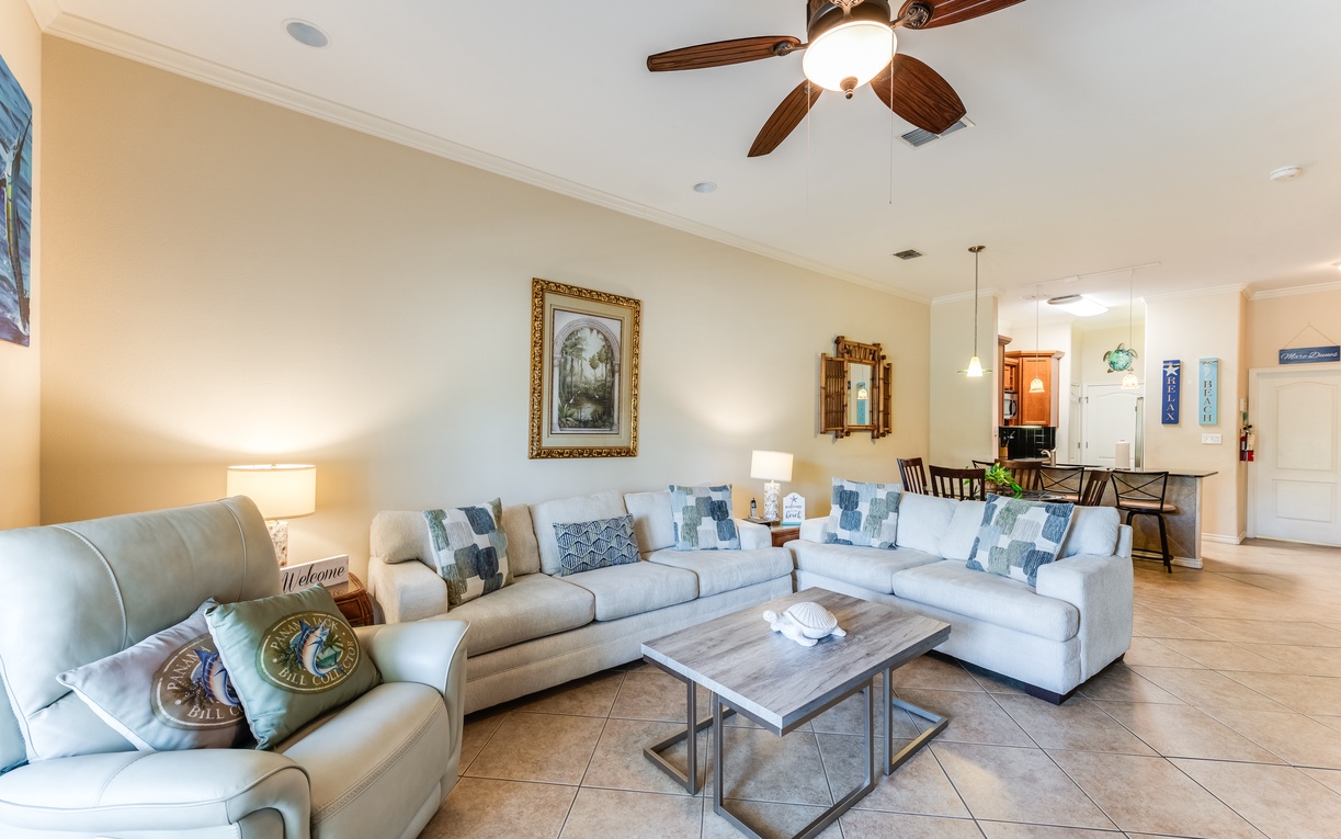 Sink into plush sectional seating where coastal-themed pillows invite relaxation beneath the gentle whir of your ceiling fan.
