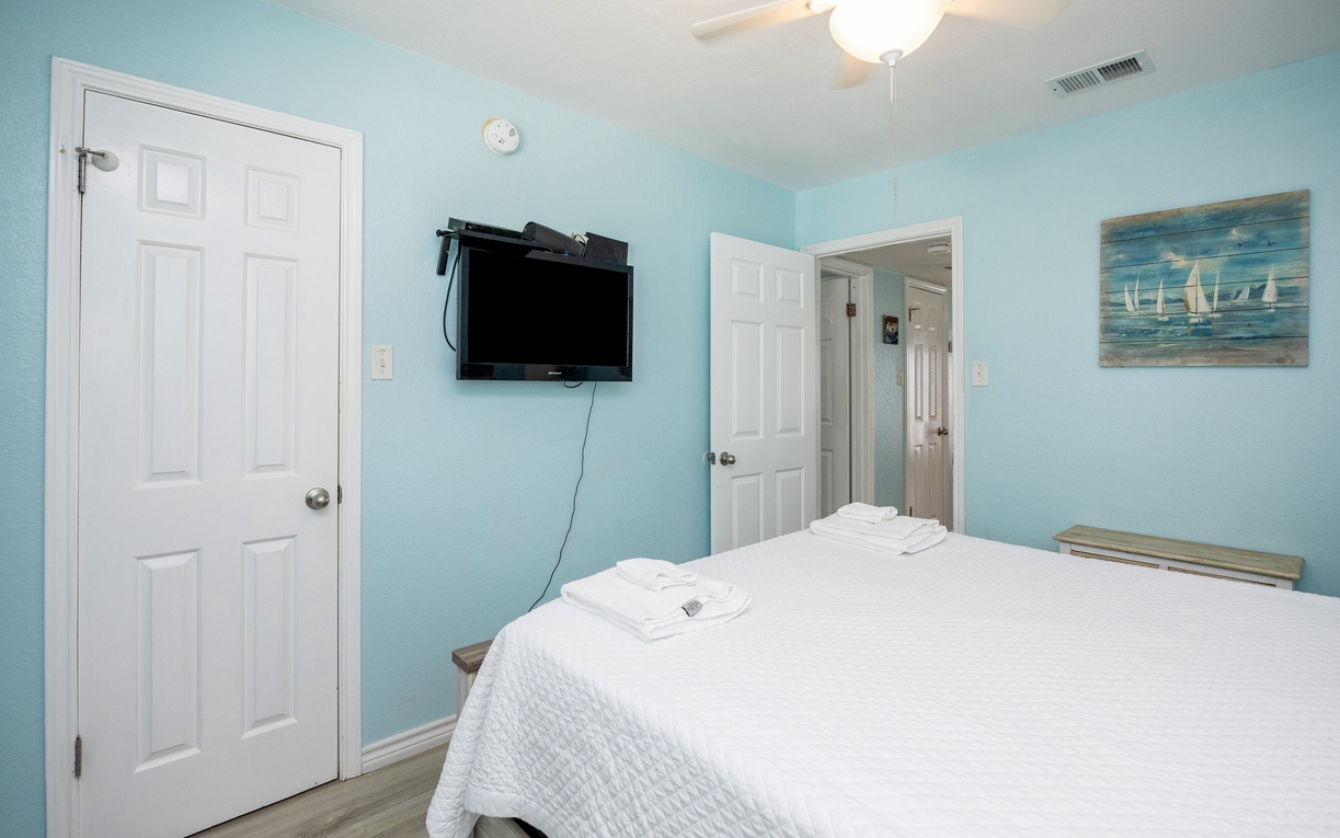 Rest in your peaceful bedroom featuring soft sea-blue walls, crisp white linens, and beach-themed artwork that creates a coastal sanctuary.