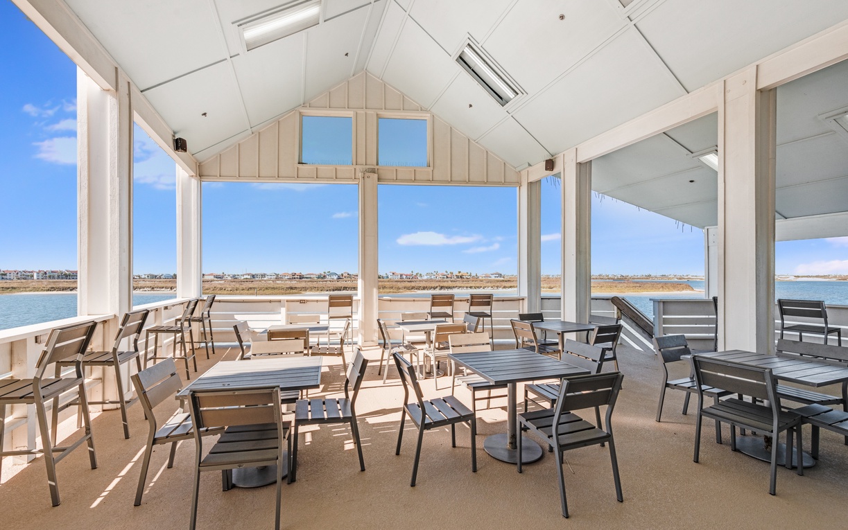 Bright waterfront dining with panoramic windows overlooking scenic coastline and blue skies.