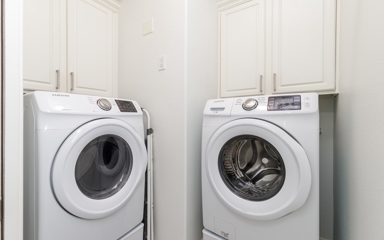 Your private laundry room features full-size Samsung washer and dryer with elegant white cabinetry for convenient storage.