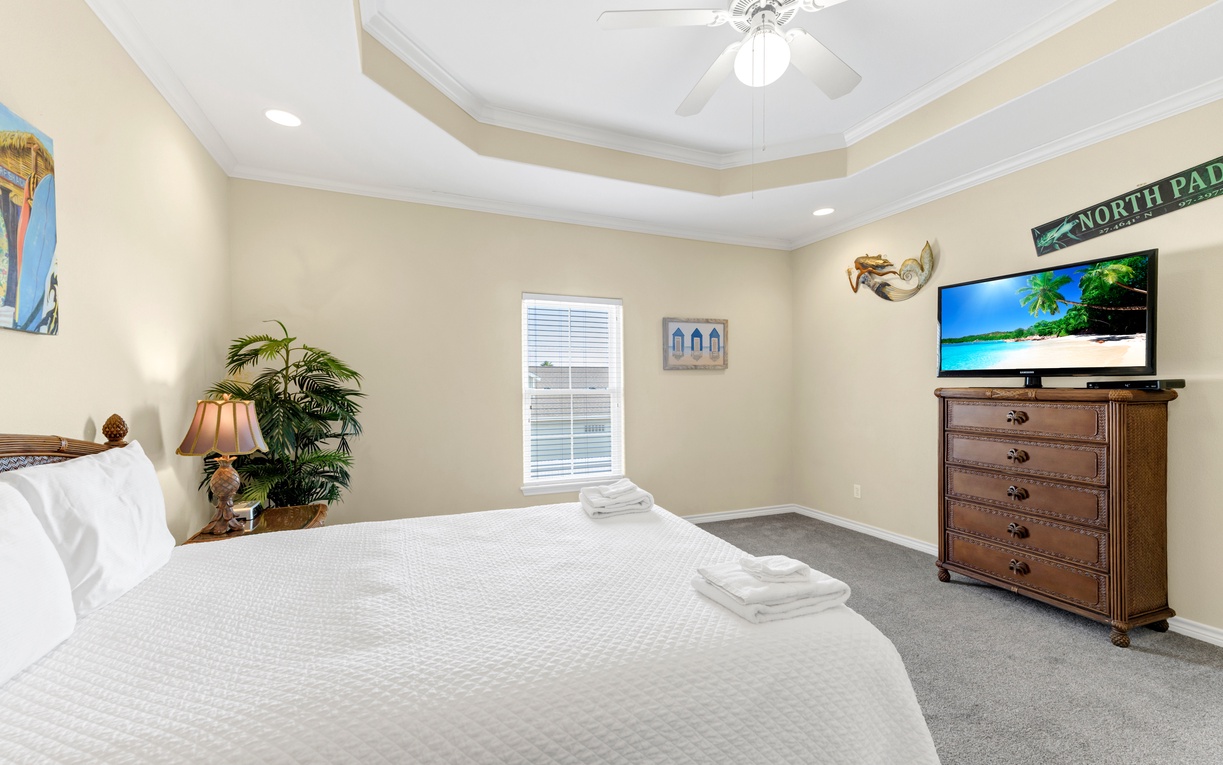 Unwind in your spacious bedroom featuring coastal decor, comfortable bedding, and entertainment center for relaxing evenings.