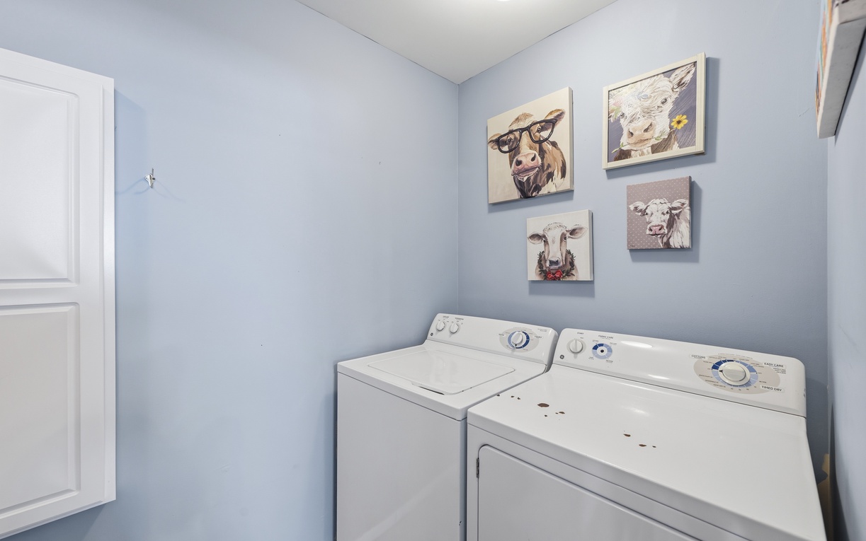 Your laundry stays fresh and clean with a full-size washer and dryer tucked away in a charming space adorned with cheerful farmhouse art, making chores feel effortless.