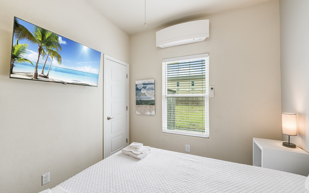 Your peaceful bedroom features a comfortable bed, crisp linens, and tropical artwork that sets a relaxing vacation mood.