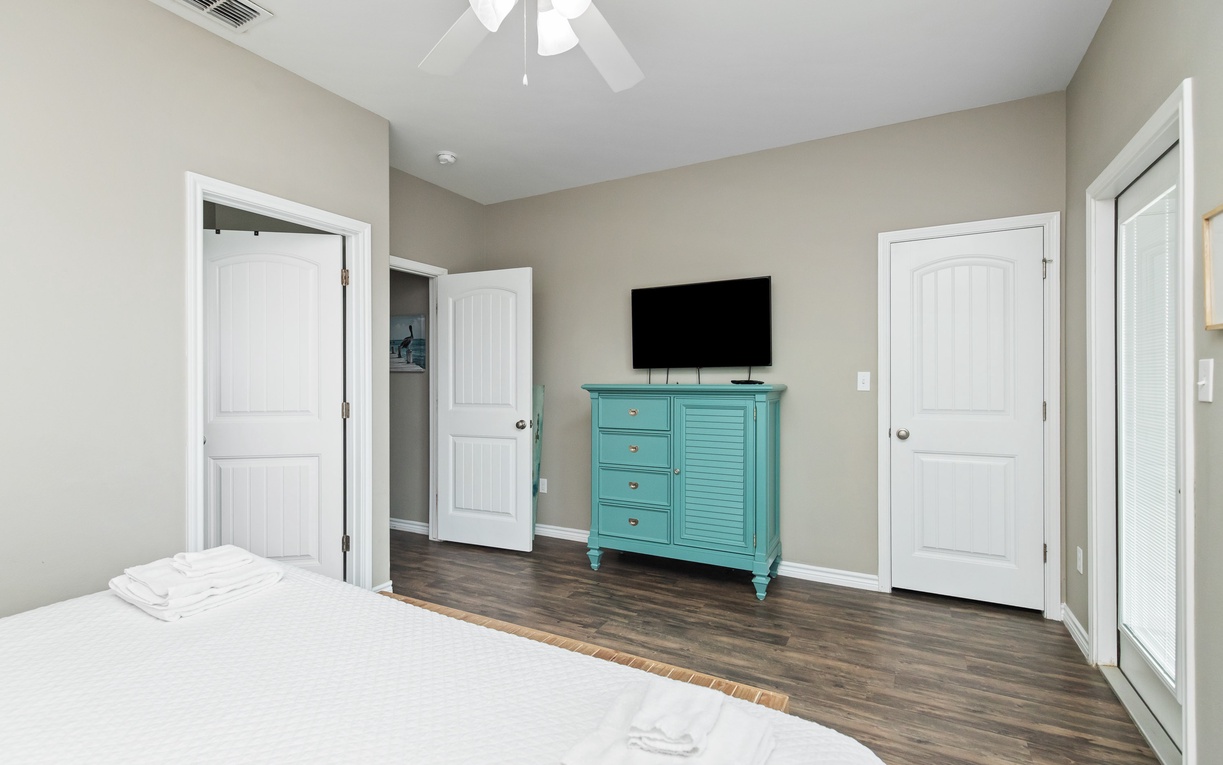 Unwind in your peaceful bedroom featuring a mounted flat-screen TV and charming turquoise dresser for all your belongings.