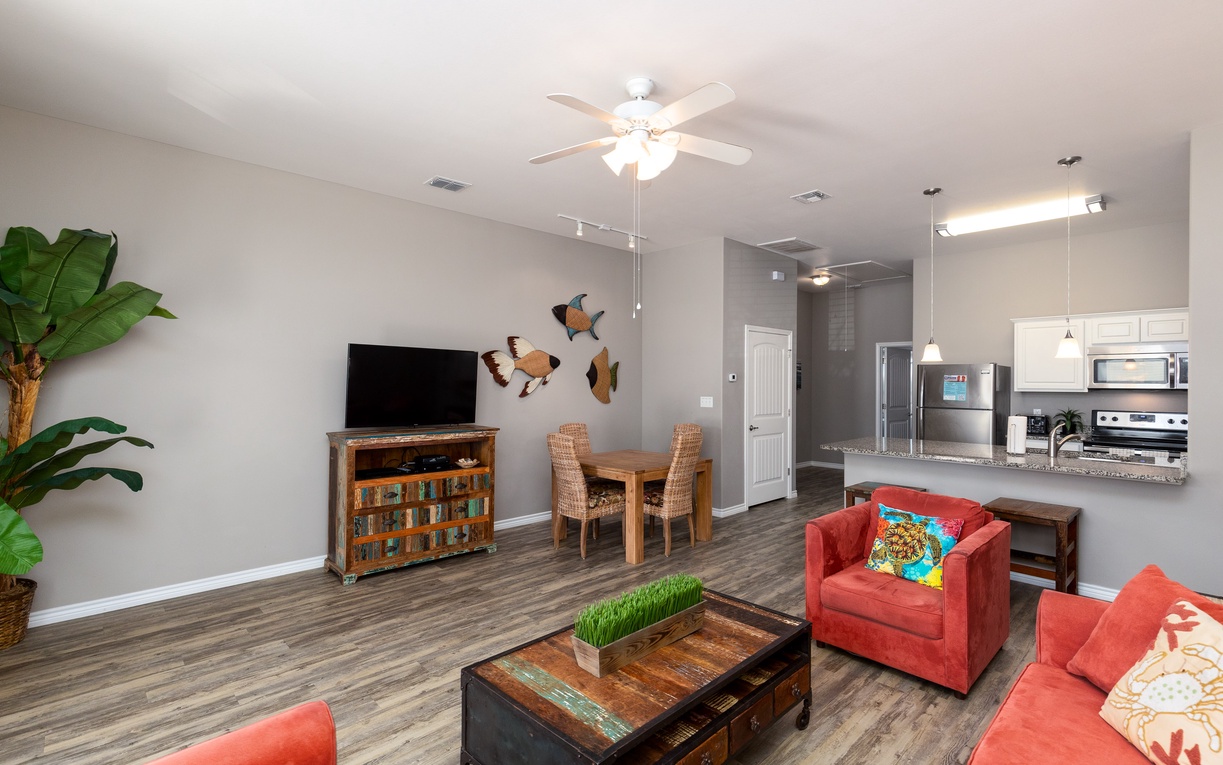 Relax in your spacious open-plan living area featuring vibrant coral seating, modern kitchen, and tropical touches that create a welcoming home away from home.