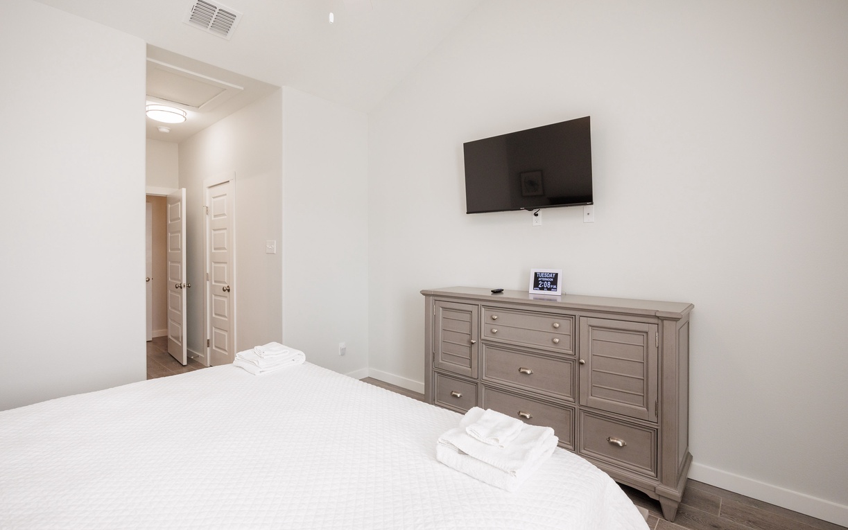 Unwind in your serene bedroom with plush white linens, entertainment at your fingertips, and thoughtful touches for a restful stay.
