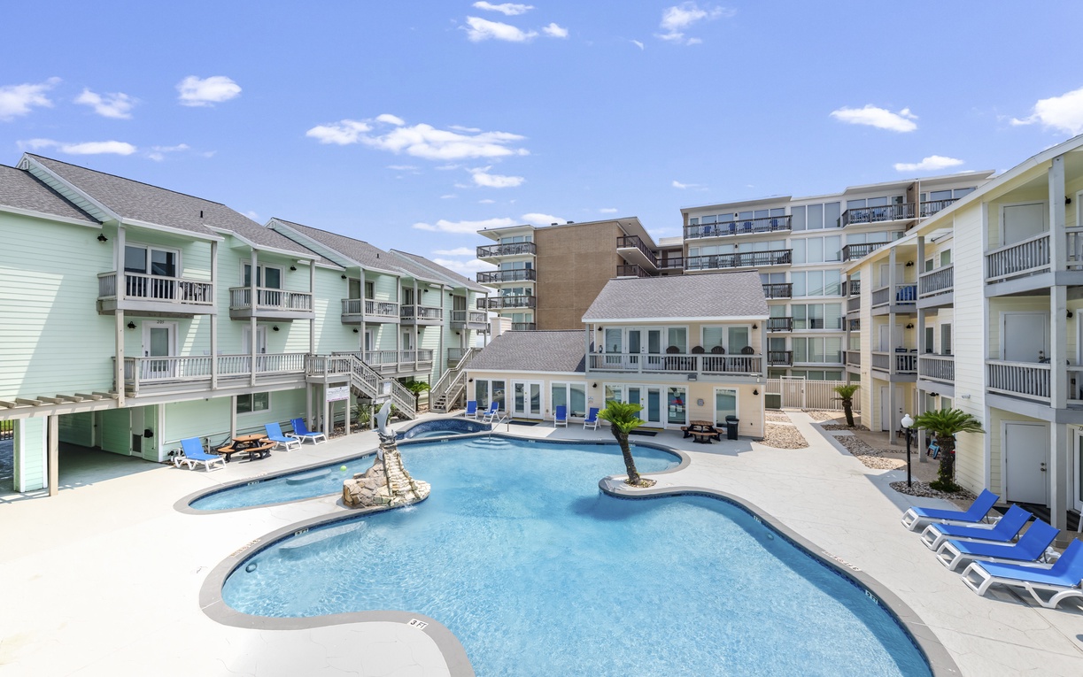 The property features a free-form pool with islands and loungers, surrounded by multi-level buildings with private balconies and easy access to all accommodations.