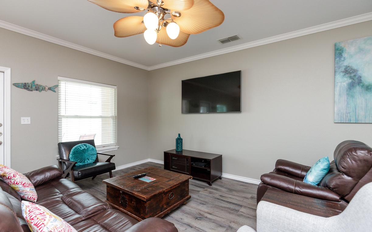 Sink into plush leather recliners and unwind in your spacious living room, complete with tropical ceiling fan and entertainment center for cozy evenings.