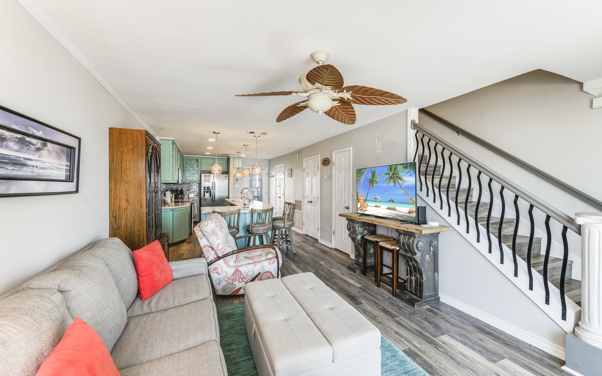 Relax in your beautifully appointed living space with tropical ceiling fan, cozy seating, and turquoise kitchen accents creating the perfect coastal retreat.
