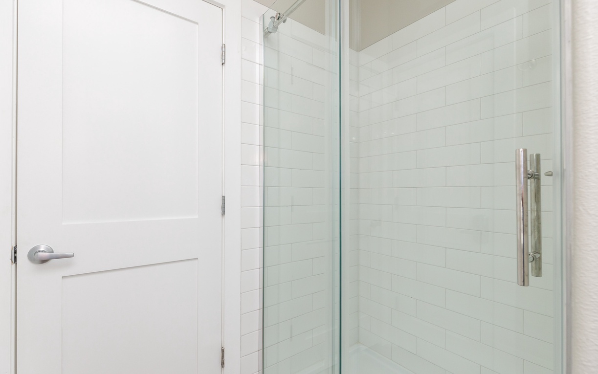 Step into your pristine glass-enclosed shower with elegant white subway tiles and modern fixtures for a refreshing start to your day.