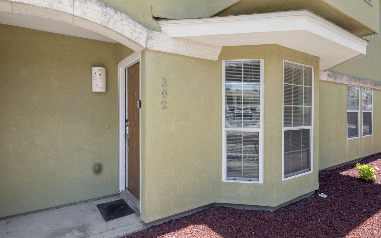 A welcoming entrance awaits at this single-story property, featuring a secure covered entryway and bright windows that frame the home's comfortable interior spaces.