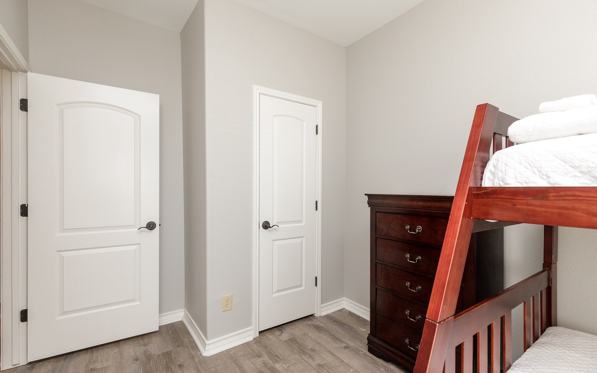 Your kids will love this cozy bunk room with plenty of storage space in the elegant wooden dresser.