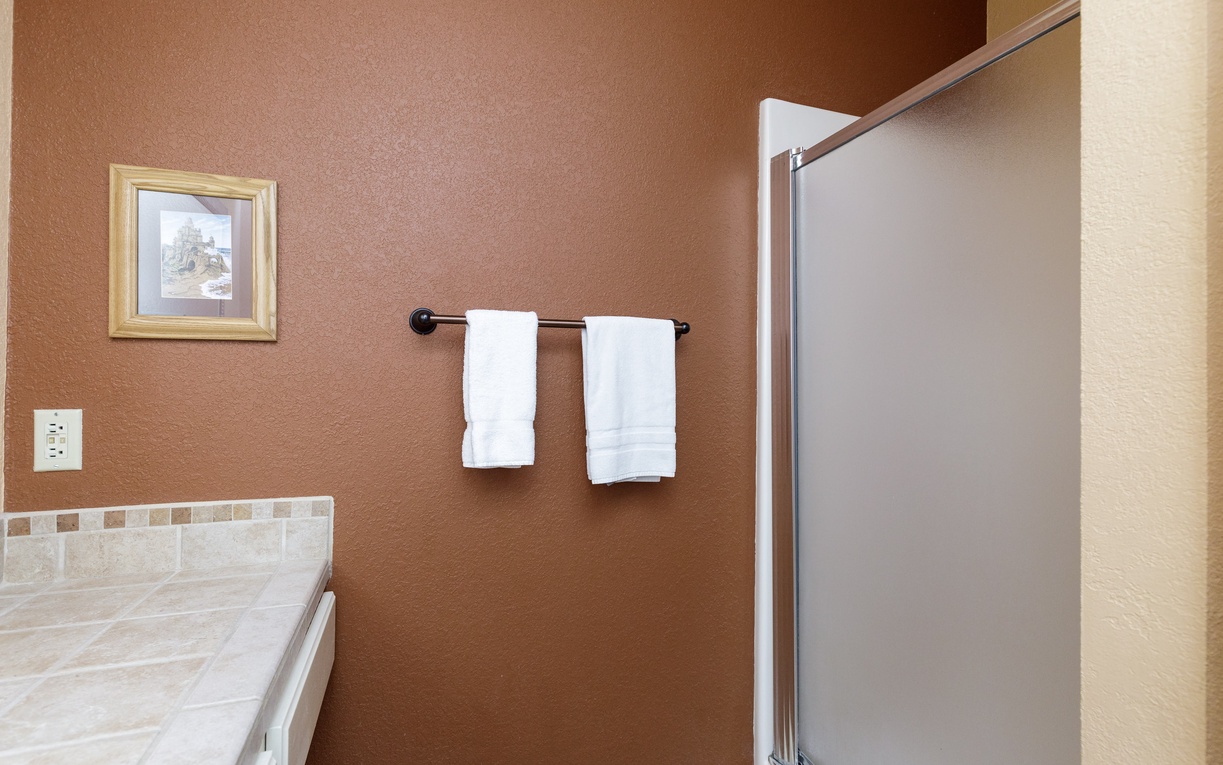 Your private bathroom features fresh towels and a spacious shower with glass doors for your comfort and convenience.