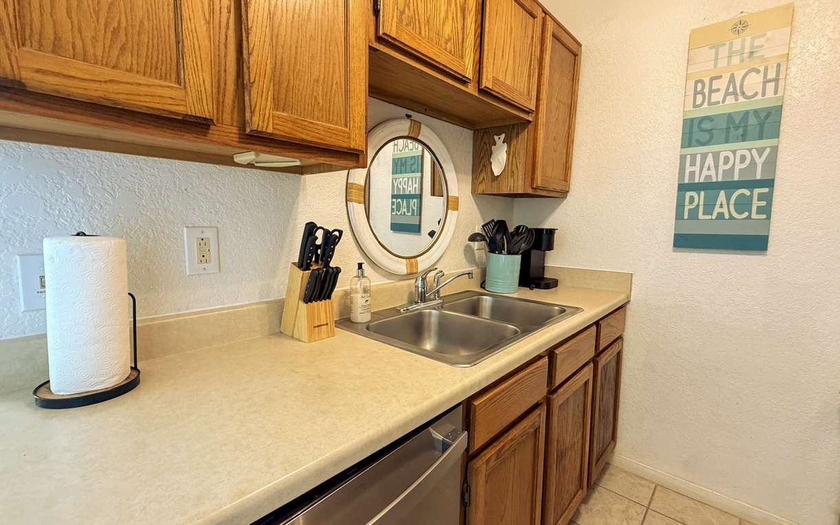 Your fully equipped kitchen awaits with everything you need to prepare meals, featuring warm wood cabinets and cheerful beach-themed decor.