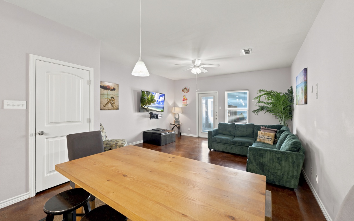 Settle into this inviting open-concept space where gleaming wood floors and high ceilings create an airy, welcoming atmosphere. Relax on plush sofas or gather around the spacious dining table—perfect for shared meals and making memories.