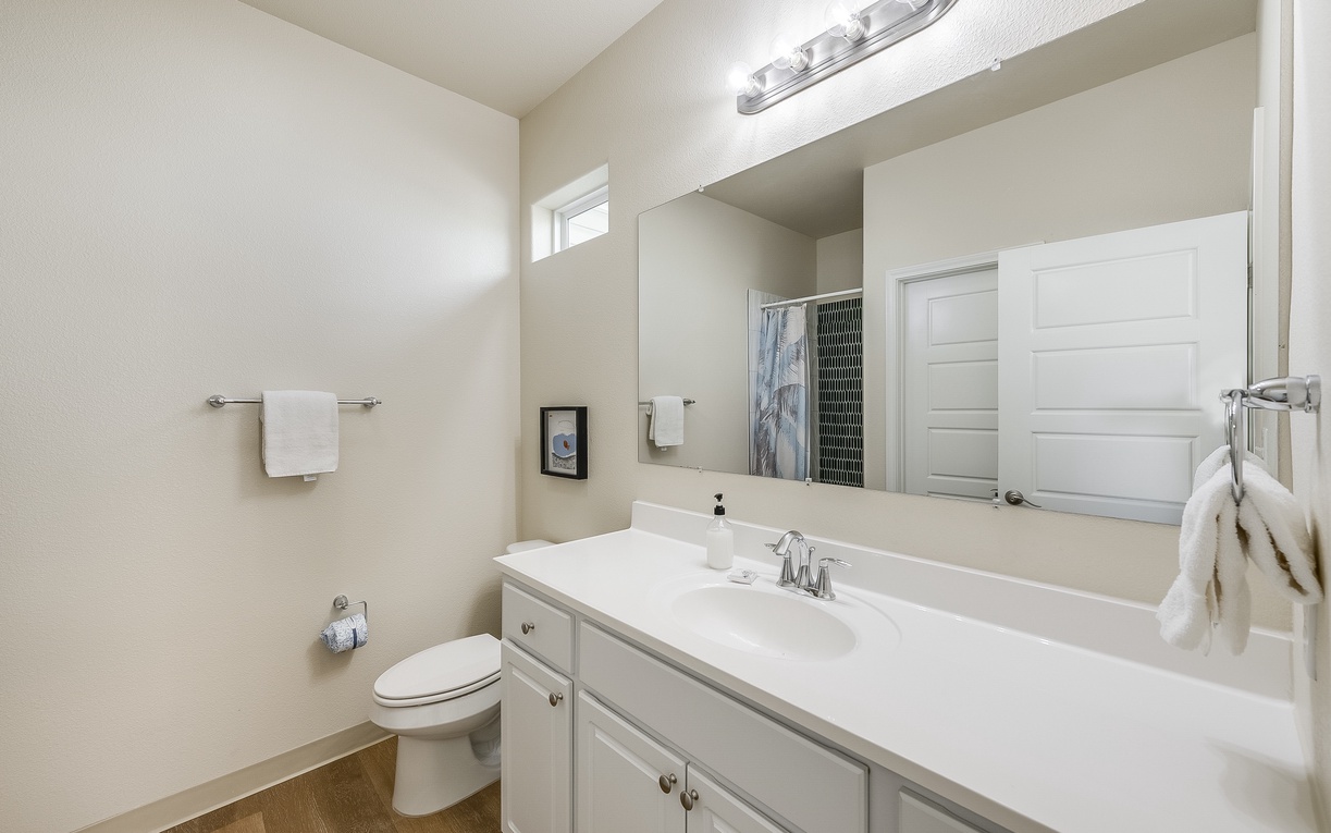Step into your pristine bathroom featuring a spacious vanity with ample storage and crisp white finishes for your morning routine.