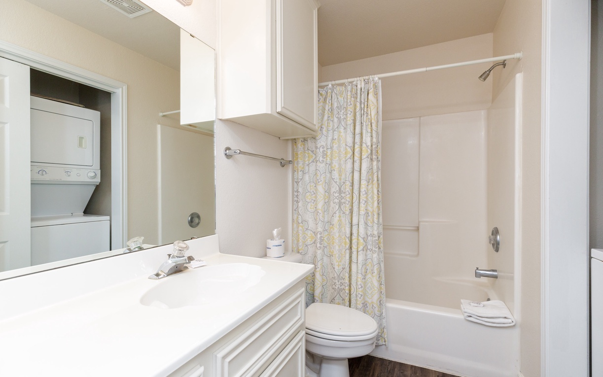 Your pristine bathroom features a relaxing tub-shower combo with elegant marble-style surround and fresh towels awaiting your arrival.