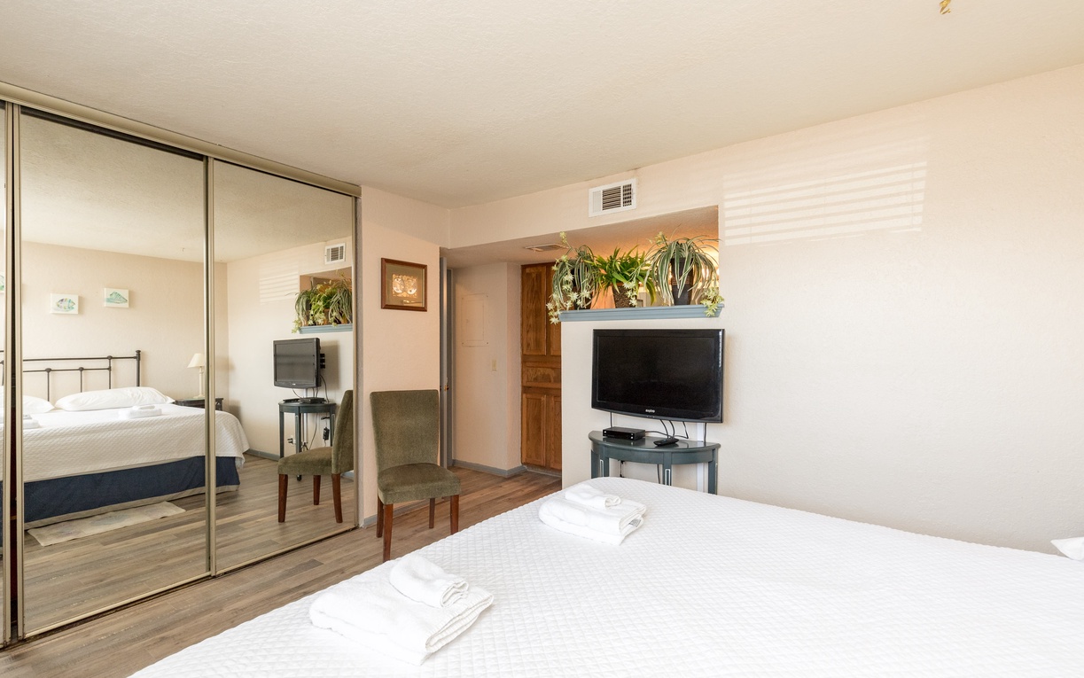 Relax in your bright bedroom with mirrored closets, flat-screen TV, and cozy seating area perfect for unwinding after exploring.
