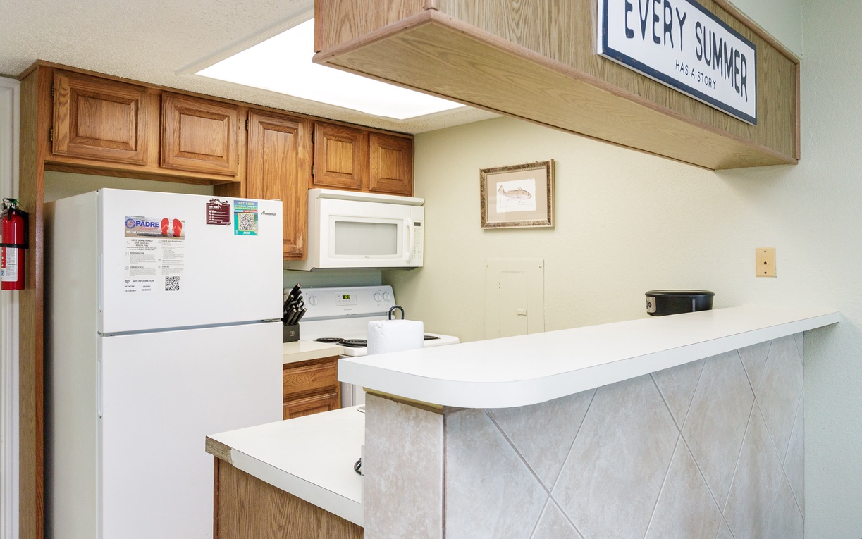 Your fully equipped kitchen features warm wood cabinets, modern appliances, and a bright breakfast bar perfect for casual meals.
