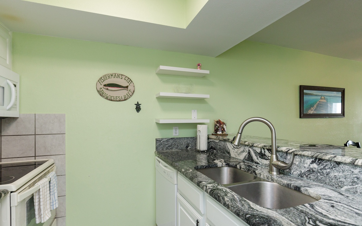 Your fully equipped kitchen features granite counters, modern appliances, and charming coastal decor—perfect for preparing fresh meals during your stay.