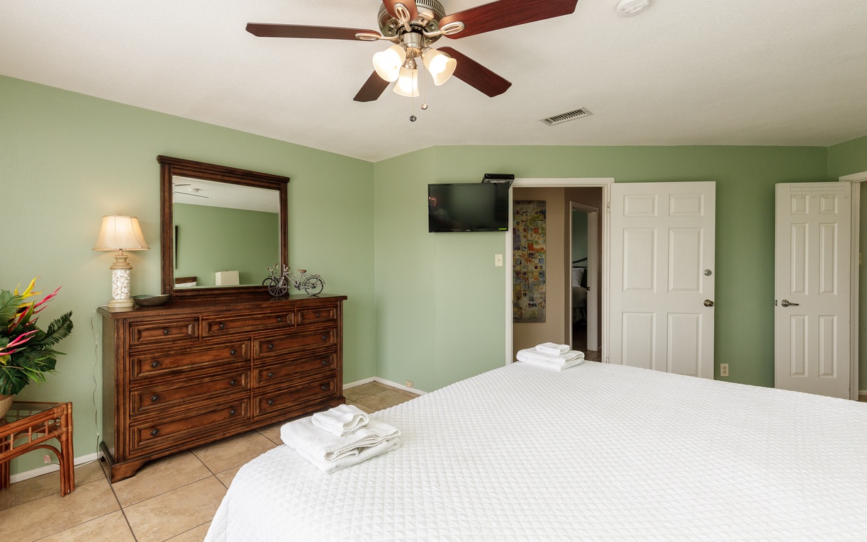 Unwind in your primary bedroom with a king size bed, elegant wood furniture, and fresh linens waiting for your arrival.