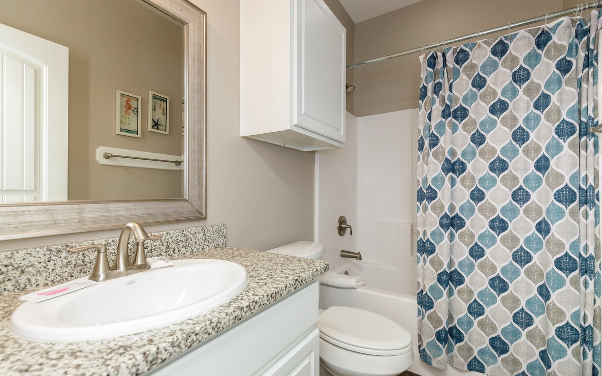 Step into your beautifully appointed bathroom with granite countertops, stylish mirror, and refreshing shower with decorative curtain.