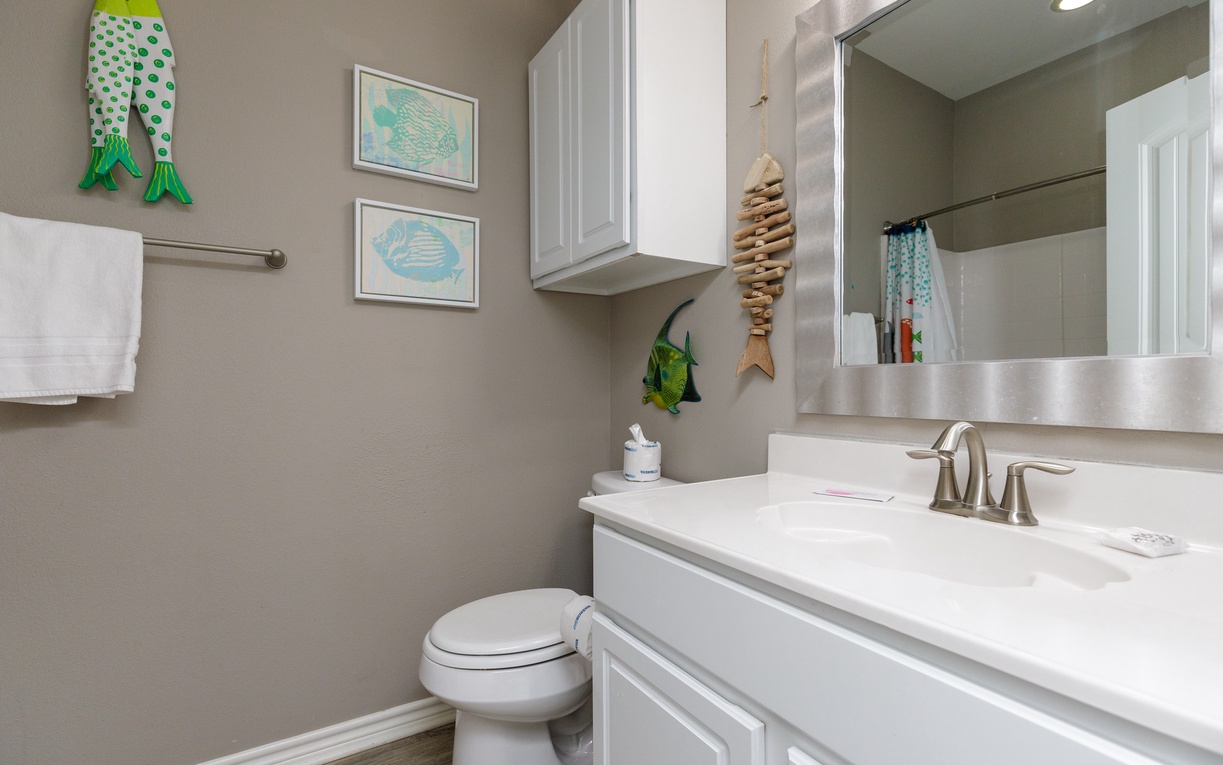 Refresh in your charming coastal bathroom with playful fish art, plush towels, and clean white fixtures creating a serene seaside retreat.