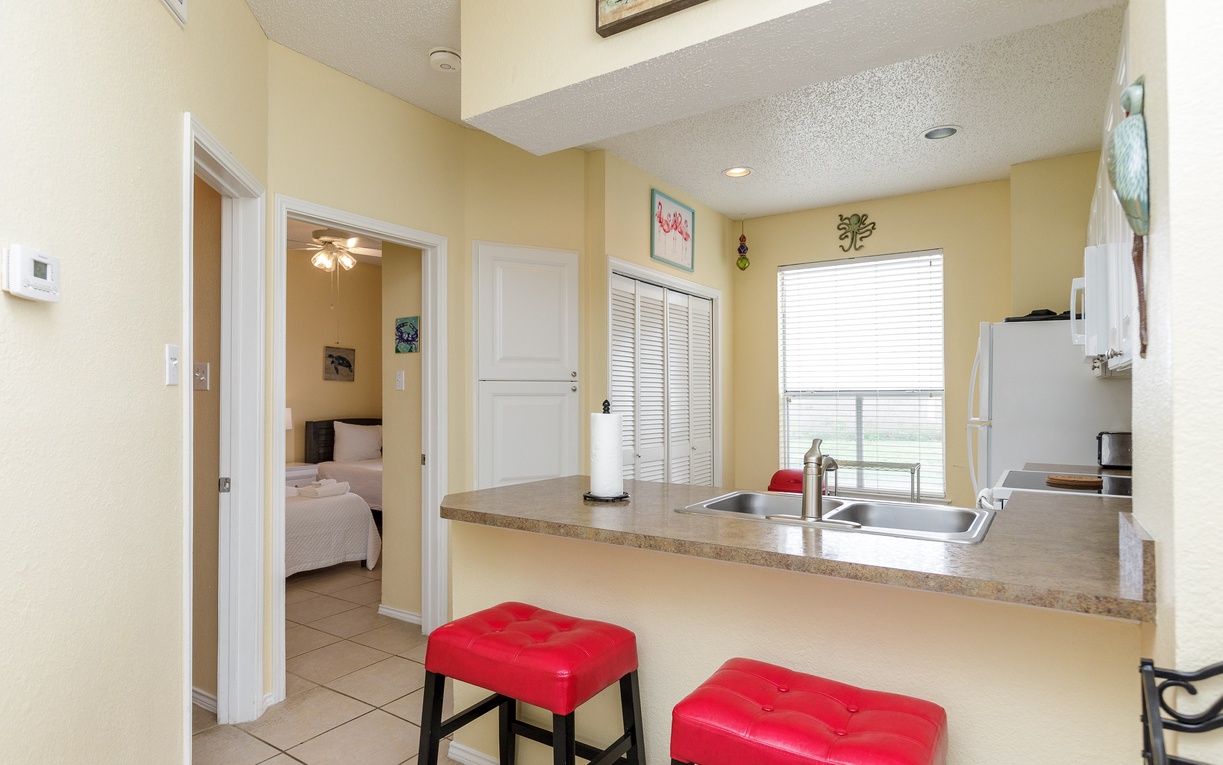 Step into your spacious kitchen with granite countertops and bright red bar stools, perfect for morning coffee or casual dining.