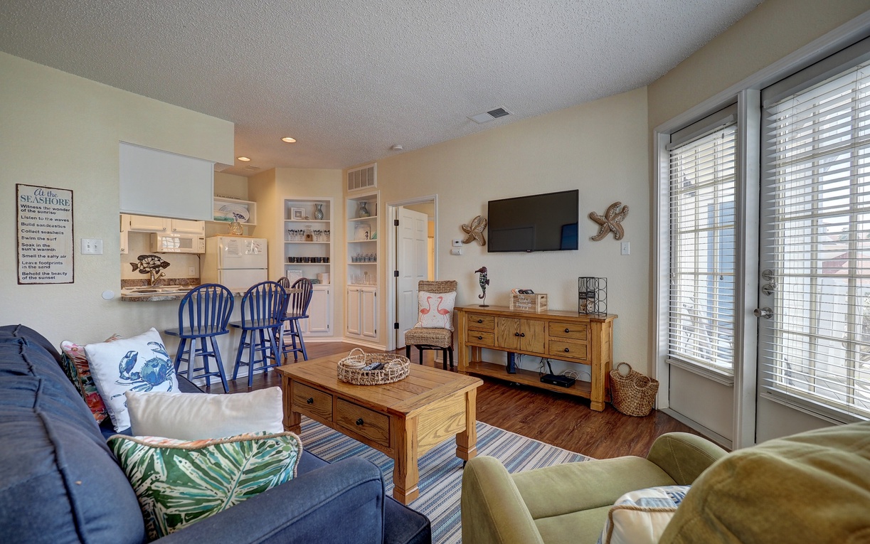 Relax in your coastal-themed living space with comfortable seating, nautical touches, and an open kitchen perfect for family meals.